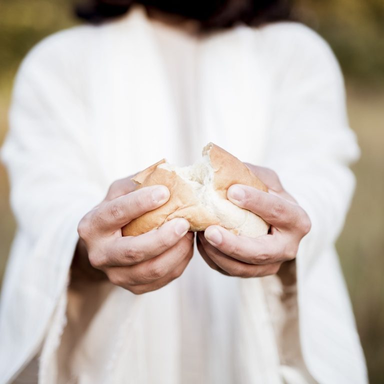 A closeup shot of Jesus Christ splitting the bread with a blurred background